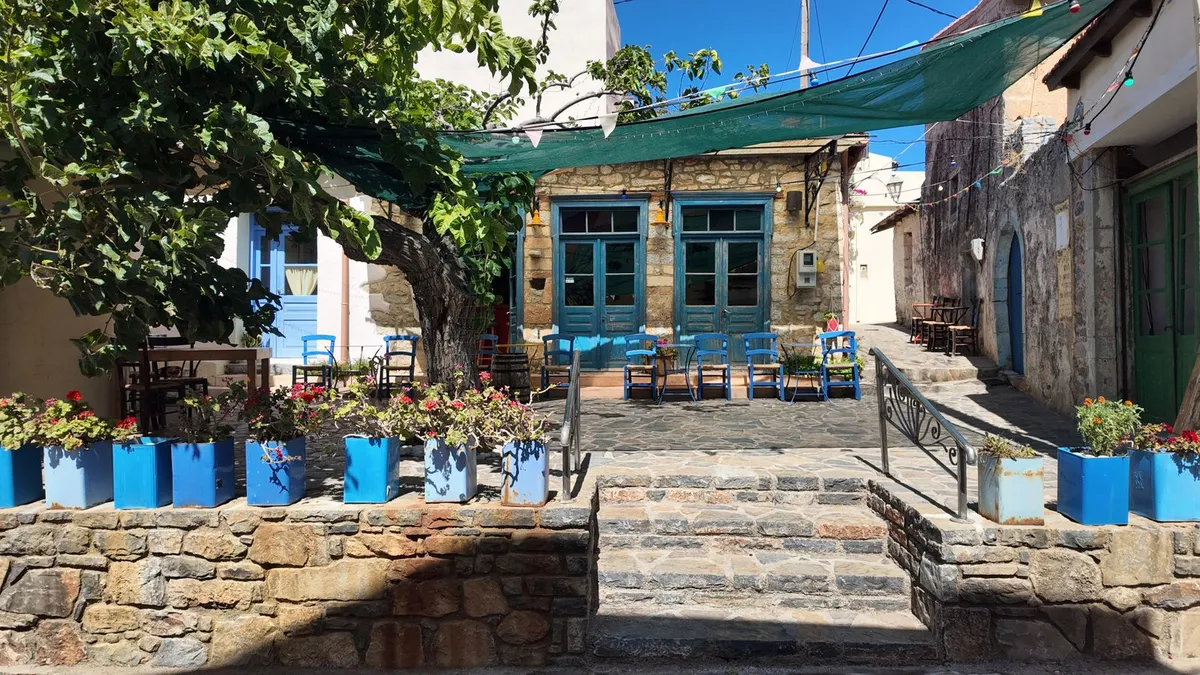 Ελληνική ταβέρνα με μπλε καρέκλες και γλάστρες σε πέτρινη αυλή